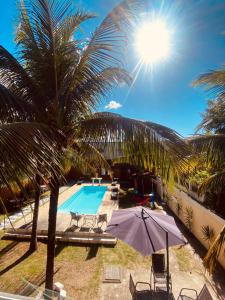 里约达欧特拉斯Residencial Costa Mar的一个带棕榈树和遮阳伞的游泳池