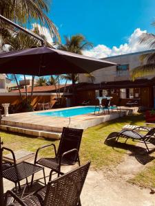 里约达欧特拉斯Residencial Costa Mar的一组椅子和一把遮阳伞,位于游泳池旁