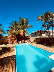 里约达欧特拉斯Residencial Costa Mar的棕榈树屋前的游泳池