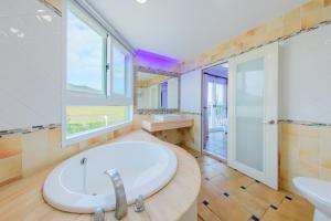 垦丁大街海的小屿渡假旅店 的大型浴室设有大浴缸和窗户。