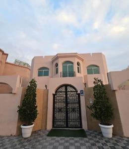 阿布扎比International Abu Dhabi Hostel的粉红色的房子,有门和两片灌木