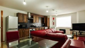 曼彻斯特THROSTLES NEST APARTMENTS的一间带红色沙发的客厅和一间厨房