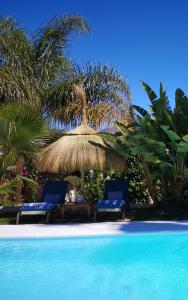 马贝拉Casa Silca的游泳池旁的两把椅子和一把草伞