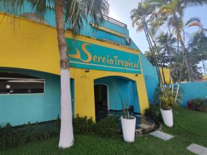 瓜鲁雅Pousada Sereia Tropical的一座黄色和蓝色的建筑,前面有棕榈树