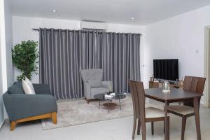 阿克拉2 Bedroom Fully Furnished Apartment的客厅配有桌椅和电视。