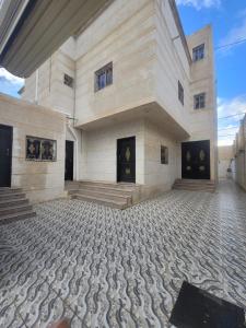 Ithnaynفلل فندقية بمدينة تنومة的一座白色的大建筑,设有石材地板和楼梯