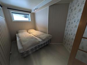 特罗姆瑟Romslig leilighet的一个小房间的小床,设有窗户
