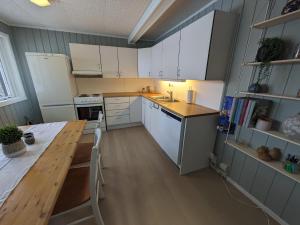 特罗姆瑟Romslig leilighet的厨房配有白色橱柜和木桌