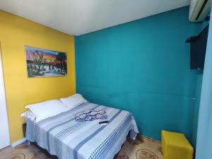 瓜鲁雅Pousada Sereia Tropical的一间卧室配有一张蓝色和黄色墙壁的床