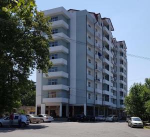 库塔伊西Cozy Apartment In Old Town Kutaisi的一座高大的白色建筑,汽车停在停车场