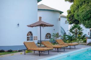 Sere KundaAfro Garden Hotel的一组椅子和一把遮阳伞,位于游泳池旁