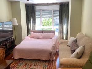 希洪Poniente Beach的一间卧室配有一张床、一张沙发和一个窗口