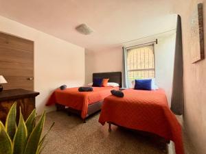 危地马拉NoMAD House的一间卧室设有两张带橙色床单的床和窗户。