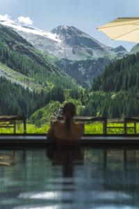 图克斯Alpinhotel Berghaus spa的坐在游泳池中的女人,享有山景