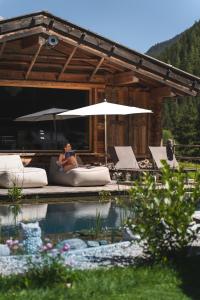 图克斯Alpinhotel Berghaus spa的坐在游泳池旁沙发上的女人