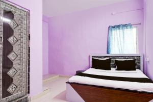 ĀsansolSPOT ON Hotel Sunshine Lodging的一间卧室配有一张紫色墙壁和窗户的床