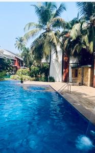 GoaLuxury apartment Blue lagoon的一座拥有蓝色海水和棕榈树的游泳池