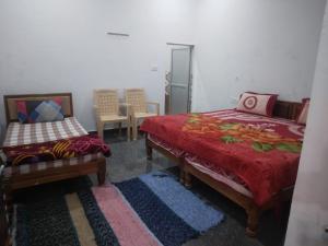 克久拉霍happy khajuraho home stay的一间卧室配有两张床、一把椅子和一张桌子