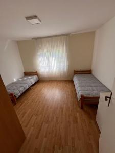 LjubovijaVikendica Lazic的大客房铺有木地板,配有两张床。