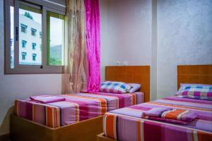 Akchourhotel el amri akchour的配有粉红色窗帘的客房内的两张床