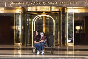 墨西哥城玛利亚伊莎贝尔墨西哥城喜来登酒店的两个女人坐在大楼前的长凳上