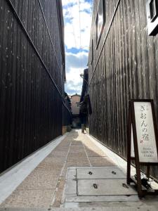 京都Kyoto Gion No Yado的中间有标志的两座建筑之间的小巷