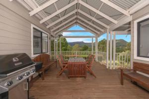 袋鼠谷Wild Rose Cottage Kiaroo Estate, Kangaroo Valley的门廊设有桌椅和烧烤架。