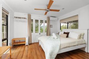 袋鼠谷Wild Rose Cottage Kiaroo Estate, Kangaroo Valley的白色卧室配有床和吊扇