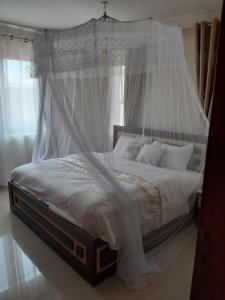 AruaVILLA FIORI APARTMENTS的卧室配有带白色床单和枕头的天蓬床。