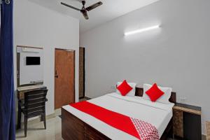 诺伊达OYO Hotel Grand Shiva的一间卧室配有一张带红色枕头的床和一张书桌