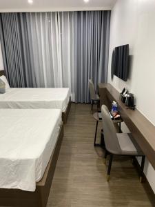 吉婆岛Sand Hotel的酒店客房带两张床和一张桌子以及椅子。