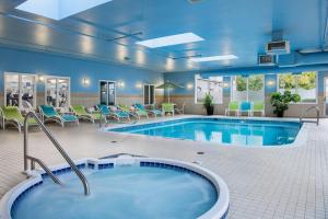 萨斯卡通萨斯卡通智选假日套房酒店的游泳池位于酒店带椅子的房间内,游泳池