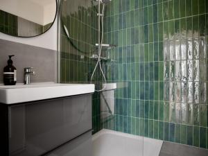 汉堡Apartmenthaus Hamburg Les Jardins的绿色瓷砖浴室设有水槽和淋浴