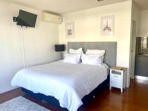 黄金海岸Self contained guest house - sleeps 4的一间卧室配有一张带白色床单的床和电视。
