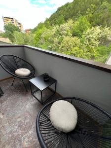 LovechApartament Varosha LUXURY的阳台配有两把椅子和一张桌子,还有一个窗户。