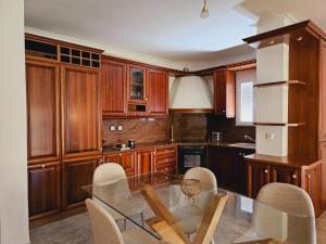 卡诺尼Corfu Villa Kanoni的厨房配有木制橱柜和玻璃桌椅