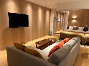 福冈belle lune hotel hakata Suite Room 1的客厅配有沙发和墙上的电视