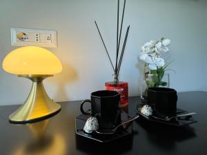 米兰MEG Glamour Suite的一张桌子,上面放着两个黑咖啡杯和一盏灯