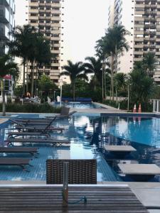 里约热内卢Apto RioCentro, Parque Olímpico Barra da Tijuca RJ的一个带椅子和棕榈树的大型游泳池