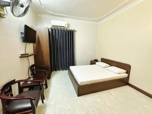 海防Đình Vũ 3 Motel的一间卧室配有一张床、一台电视和椅子