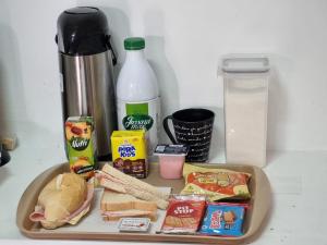 瓜鲁柳斯Villa Fátima Hostel GRU的一张桌子,上面放着食品托盘,三明治和牛奶