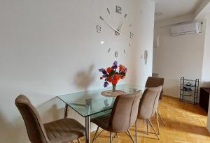 波扎雷瓦茨Apartman Panorama的用餐室配有玻璃桌、椅子和时钟