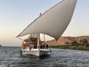 阿斯旺Dahabiya Nile Sailing-Safiya-Aswan to Luxor-every Friday-4 days-3 nights的一艘在水中装有大帆的船