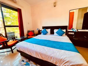 GoaHamilton Hotel & Resort Goa的一间卧室配有一张带蓝色枕头的大床