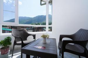 库尔卢Hotel Kullu Valley的阳台配有桌椅和窗户。