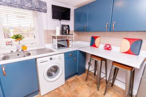 邓迪Seaview Cottage Central Dundee的厨房配有蓝色橱柜、洗衣机和烘干机