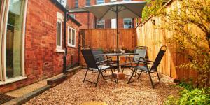 诺丁汉Single Room in Modern House near Nottingham的庭院配有桌椅和遮阳伞。