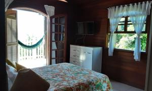 安格拉杜斯雷斯Refúgio Hangarana的一间卧室设有一张床、一台电视和两个窗户。