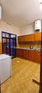 阿尔布亚米AL AMAN HOTEL的厨房配有木制橱柜和白色冰箱。