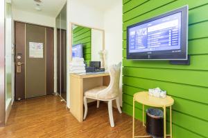 高雄Newrise Hotel的客房设有绿色的墙壁、书桌和电视。